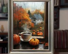 a cup of coffee sitting on top of a table next to a window covered in fall leaves