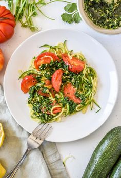 a white plate topped with zucchini noodles and tomatoes