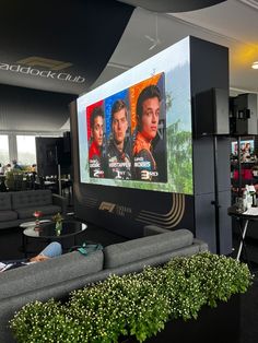 a large screen in the middle of a room with couches and tables around it