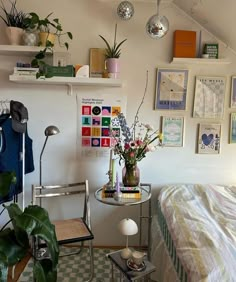 a bedroom with lots of plants and pictures on the wall above the bed, along with a small table