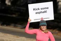 a woman holding up a sign that says kick some asphalt while walking down the street