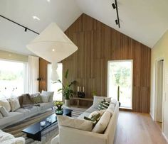 a living room filled with furniture and windows next to a wooden floor covered in white pillows