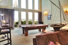 a living room filled with furniture and a pool table in front of a large window