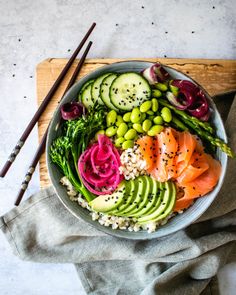 a bowl filled with rice, cucumber, avocado and other vegetables