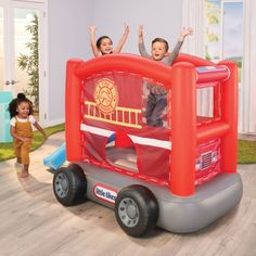 two children are playing in an inflatable bouncer with their arms up and hands raised