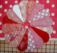 a red and white piece of fabric with polka dots on the border, sitting on a pink background