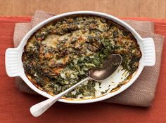 a white bowl filled with food sitting on top of a red place mat next to a silver spoon