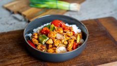 a bowl filled with rice and vegetables on top of a wooden cutting board