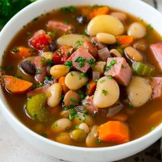 a white bowl filled with beans, ham and vegetables