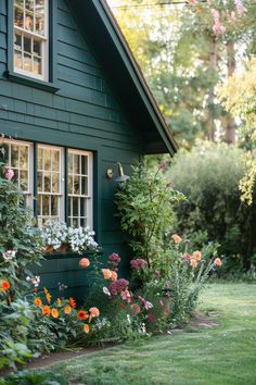 a green house with lots of flowers in the front yard