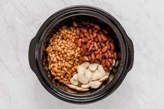 beans, cashews and other foods are in a crock pot on a marble surface