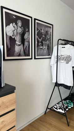 an ironing board with clothes hanging on it next to two framed pictures and a t - shirt