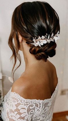 a woman wearing a bridal hair comb with flowers in it's hair, looking off to the side