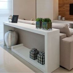 a living room with white furniture and a flat screen tv mounted on the wall above it