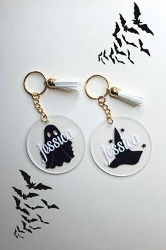 two acrylic key chains with tassels hanging from them on a white surface