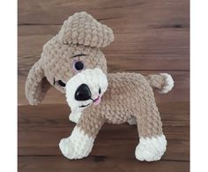 a crocheted dog is standing on a wooden floor with its head turned to the side