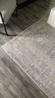 a living room with wood flooring and gray rugs on the floor in front of a couch