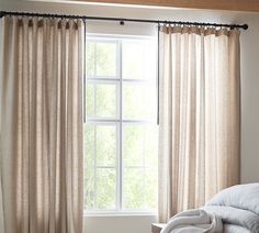 a bed sitting under a window next to a white blanket on top of a wooden floor