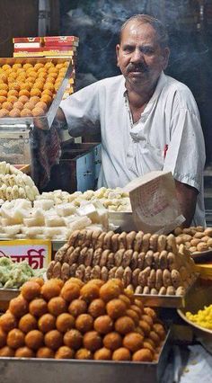 a man standing in front of a food stand filled with lots of different types of foods