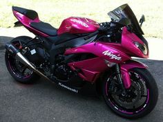 a pink motorcycle is parked on the street