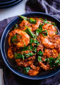 a blue bowl filled with shrimp and spinach