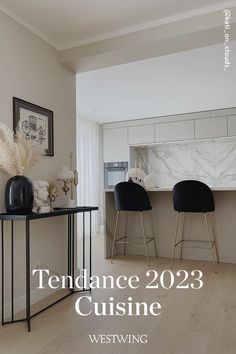 two black chairs sitting on top of a wooden floor in front of a kitchen counter