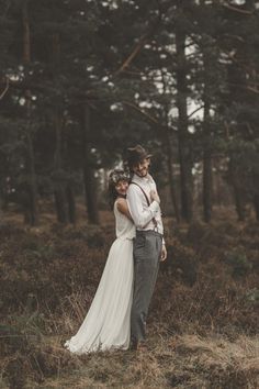 a man and woman are standing in the woods with their arms wrapped around each other