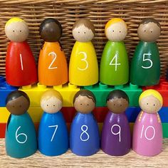 a group of wooden peg dolls sitting on top of each other in front of a basket