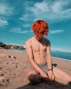 a man with red hair sitting on the beach