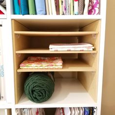 a book shelf filled with lots of different types of fabrics and fabric on top of it