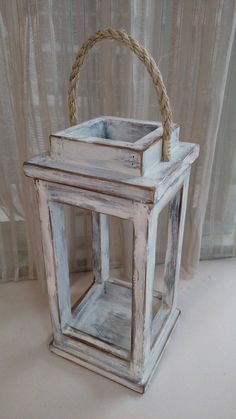 an old white wooden lantern with rope handle