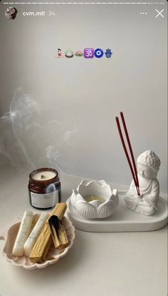 an assortment of items on a tray with candles and incense sticks in the bowl next to them