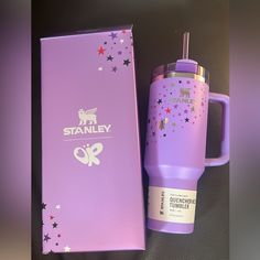 a purple starbucks cup next to a box with the name stanley on it and a straw sticking out of it