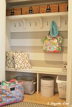 an organized mud room with striped walls and white shelves