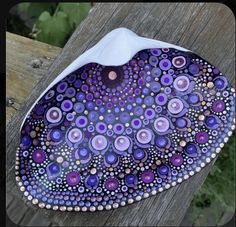 a purple and white plate sitting on top of a wooden table next to a fence