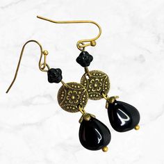 Long black beaded earrings in brass. Richly detailed brass finish Mandala connectors suspend Czech glass teardrop beads. Perfect long dangle earrings to go with everything from jeans to dress up. These Bohemian earrings are a wardrobe must-have! Hypoallergenic ear wires (nickel and lead free). Choose ear wires at checkout.  Artisan glass beads produced in small quantities in the Czech Republic. A gift for you or someone special, earrings are carded and in an organza bag. Available in ANTIQUE COP Nickel-free Brass Beaded Teardrop Earrings, Teardrop Brass Beaded Earrings With Ear Wire, Nickel-free Teardrop Beaded Brass Earrings, Nickel-free Brass Teardrop Beaded Earrings, Elegant Brass Beaded Earrings With Round Beads, Elegant Brass Beaded Earrings, Elegant Brass Teardrop Beaded Earrings, Elegant Adjustable Brass Beaded Earrings, Elegant Teardrop Beaded Brass Earrings