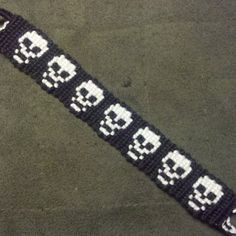 a black and white beaded wristband with skulls on it, in the shape of numbers