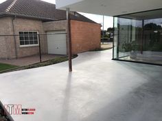 an empty concrete patio in front of a brick building with glass doors and windows on the side