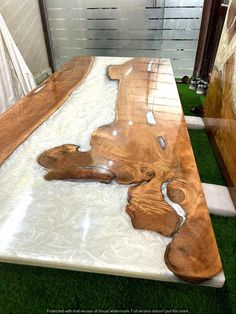 a wooden table sitting on top of a green carpeted floor next to a white wall