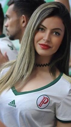 a woman with long blonde hair wearing a white shirt and green trim around her neck