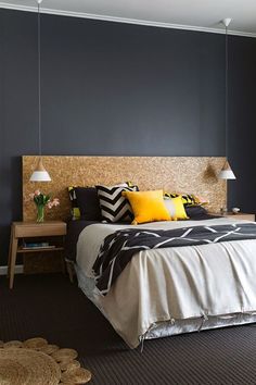 a bedroom with black walls and yellow pillows on the headboard, along with carpeted flooring