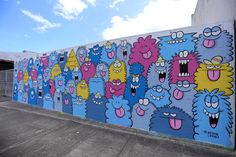 a wall with many cartoon characters painted on it and blue sky in the back ground