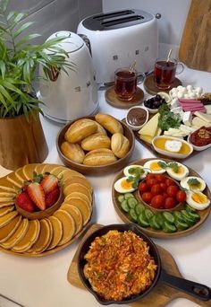 a table topped with plates of food and bowls of fruit next to an air fryer