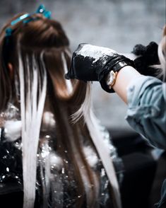 a woman is getting her hair done by another person with long white and blonde hair