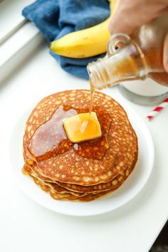 a person pouring syrup on top of some pancakes