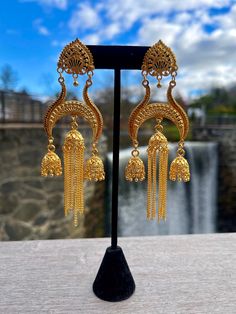 Jhumkas are a popular earring style in India and other South Asian countries. They are often crafted with a gold or silver finish and commonly adorned with pearls or gemstones. Jhumkas typically feature a large teardrop-shaped pendant that hangs from the earlobe, with smaller pendants dangling from the bottom of the main pendant. These earrings are known for their striking and elaborate design. Festive Gold Chandbalis With Latkans, Bollywood Gold Chandbalis With Latkans, Bollywood Style Gold Chandbalis With Latkans, Gold Temple Jewelry Chandbalis With Latkans, Gold Chandbalis With Latkans In Temple Jewelry Style, Celebration Brass Chandbalis With Latkans, Festive Latkans Jhumkas Dangle Earrings, Brass Bridal Earrings With Latkans For Diwali, Diwali Brass Bridal Earrings With Latkans