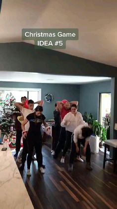 a group of people standing in a living room next to a christmas tree on top of a hard wood floor