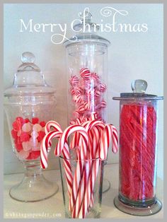 some candy canes are in a glass vase and on the table is a jar