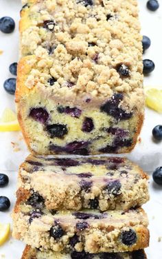 two slices of blueberry crumb bread on a white surface with lemon wedges