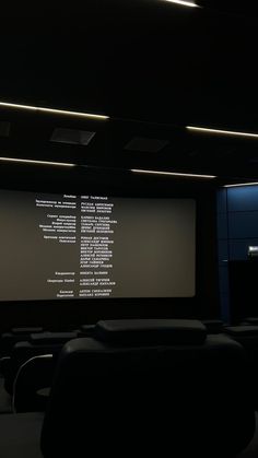 a large screen in the middle of a dark room with rows of seats on either side